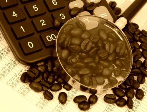 Coffee beans, calculator and magnifying glass in sepia tone, original source: Shutterstock