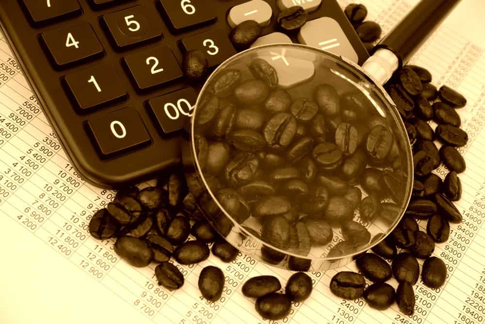 Coffee beans, calculator and magnifying glass in sepia tone, original source: Shutterstock