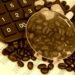 Coffee beans, calculator and magnifying glass in sepia tone, original source: Shutterstock